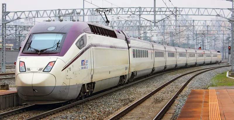 White KTX-Sancheon high-speed train with a purple nose arriving on a curve at Daejeon Station