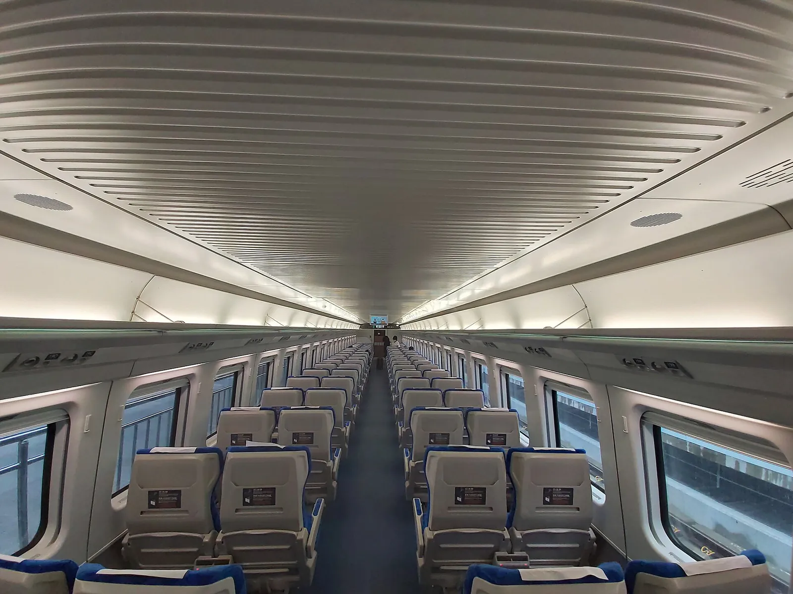Standard-class carriage of a KTX-Eum train with rows of grey seats, four abreast, and screens on the seatbacks