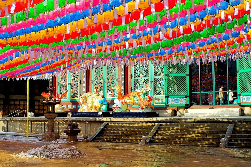 Rows of brightly coloured paper lanterns hanging over the courtyard in front of the main hall of Jogyesa Temple in Seoul