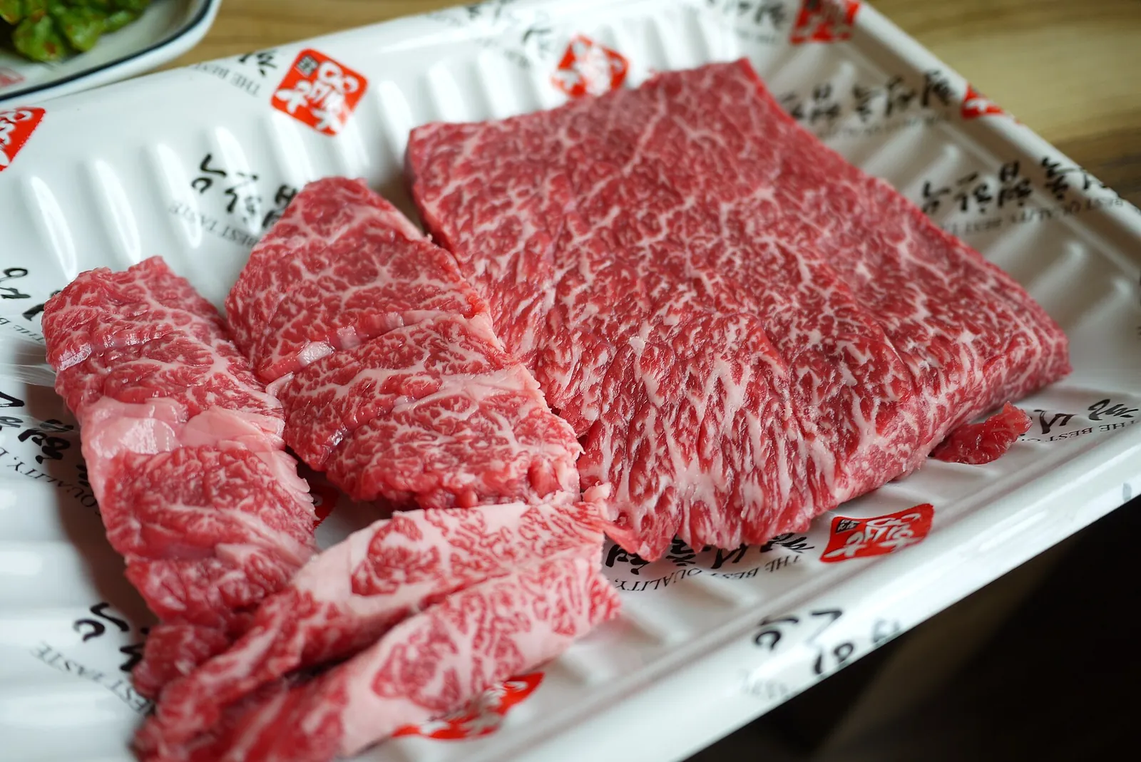 Thick slices of deep-red, finely marbled raw Hoengseong hanu beef on a white tray