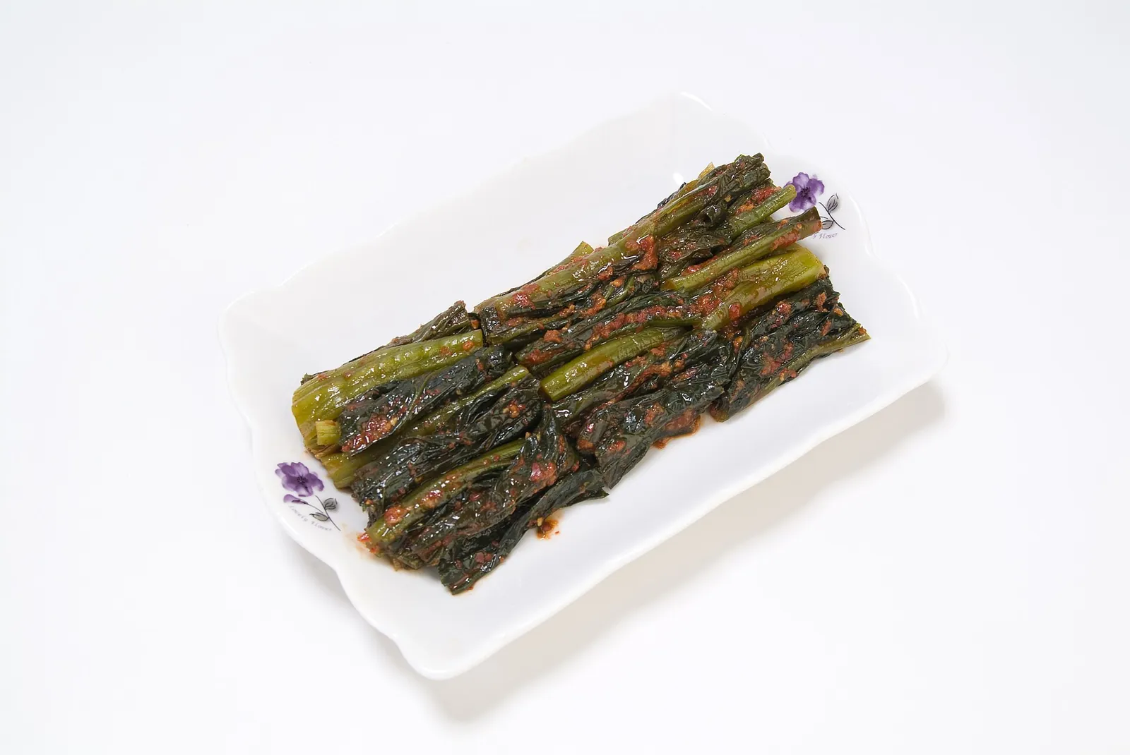 Whole stalks of red-seasoned gat kimchi (leaf mustard kimchi) laid on a white plate
