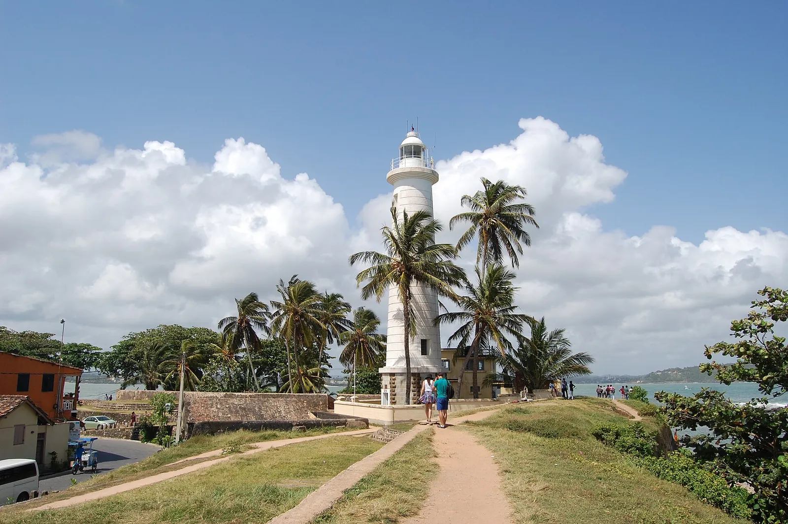 Farul alb din Galle Fort printre palmieri, văzut de pe iarba de lângă ziduri