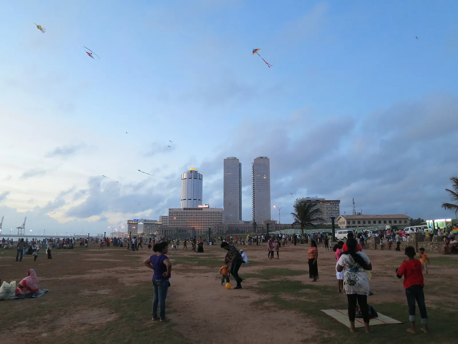 Famiglie e persone che fanno volare gli aquiloni sul prato di Galle Face Green con i grattacieli di Colombo sullo sfondo