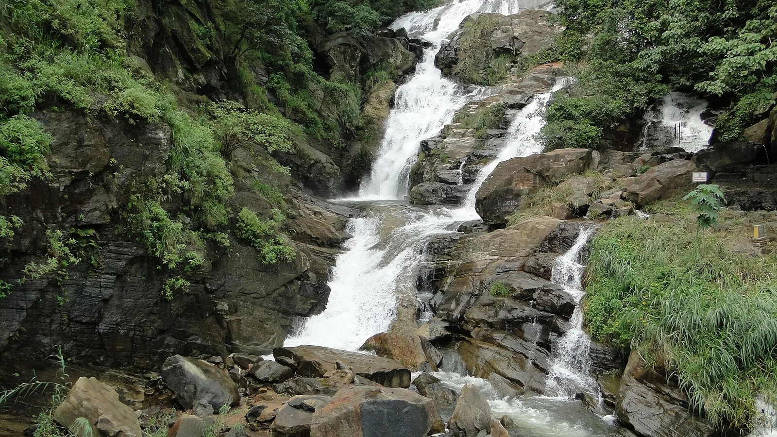 Las cascadas de Ravana cayendo sobre rocas oscuras junto a un bosque verde