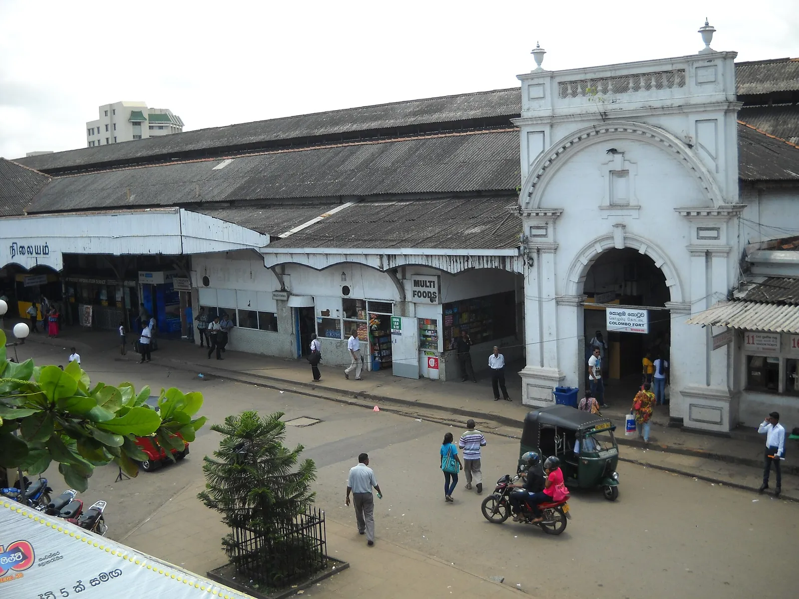 La entrada blanca con arcos de la estación de tren de Colombo Fort, con tuk-tuks y un autobús delante