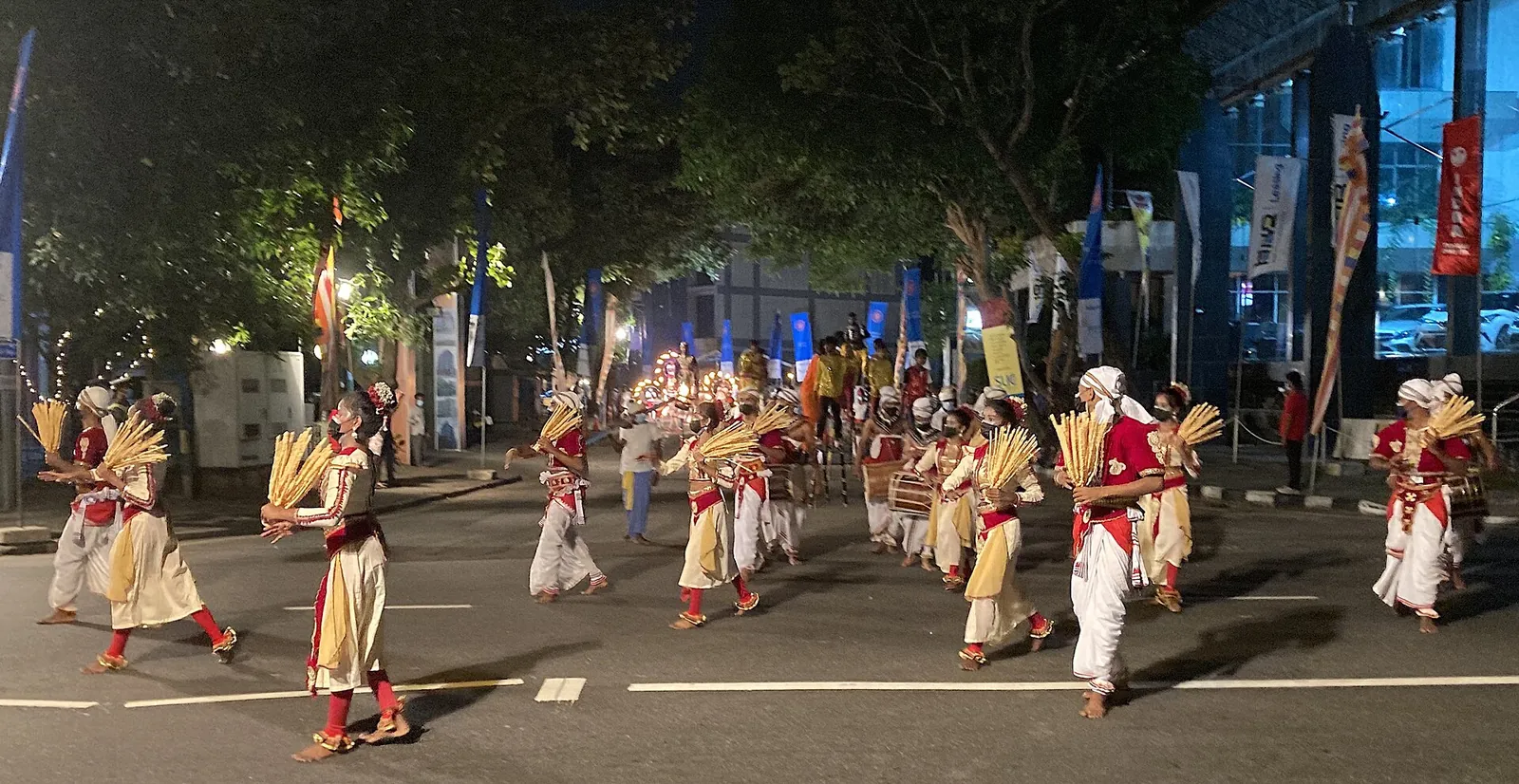 Tanečníci v bílých a červených kostýmech na silnici při Navam Perahera chrámu Gangaramaya Temple v Colombu