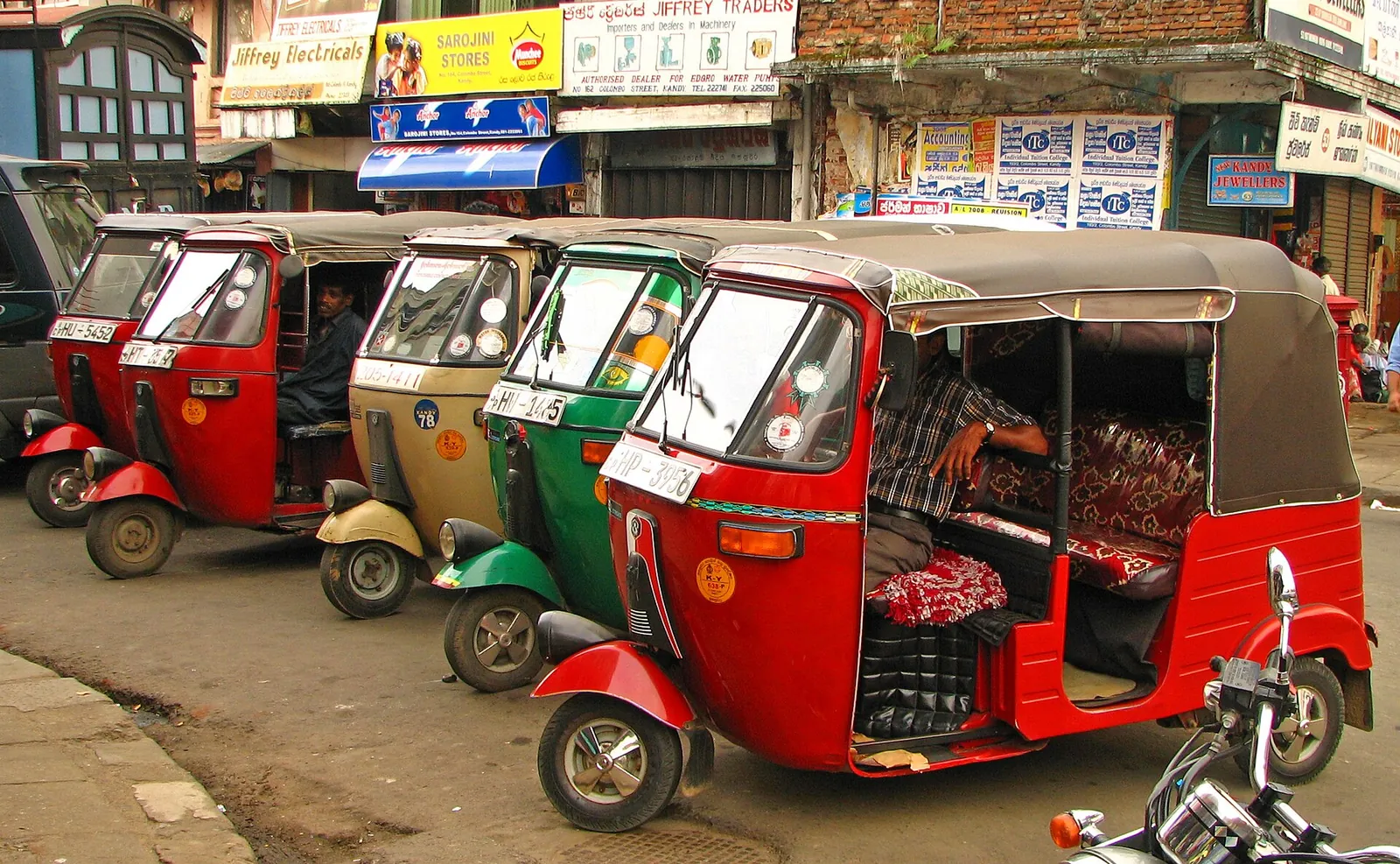 Eine Reihe bunter Tuk-Tuks, die in einer Straße in Kandy auf Fahrgäste warten