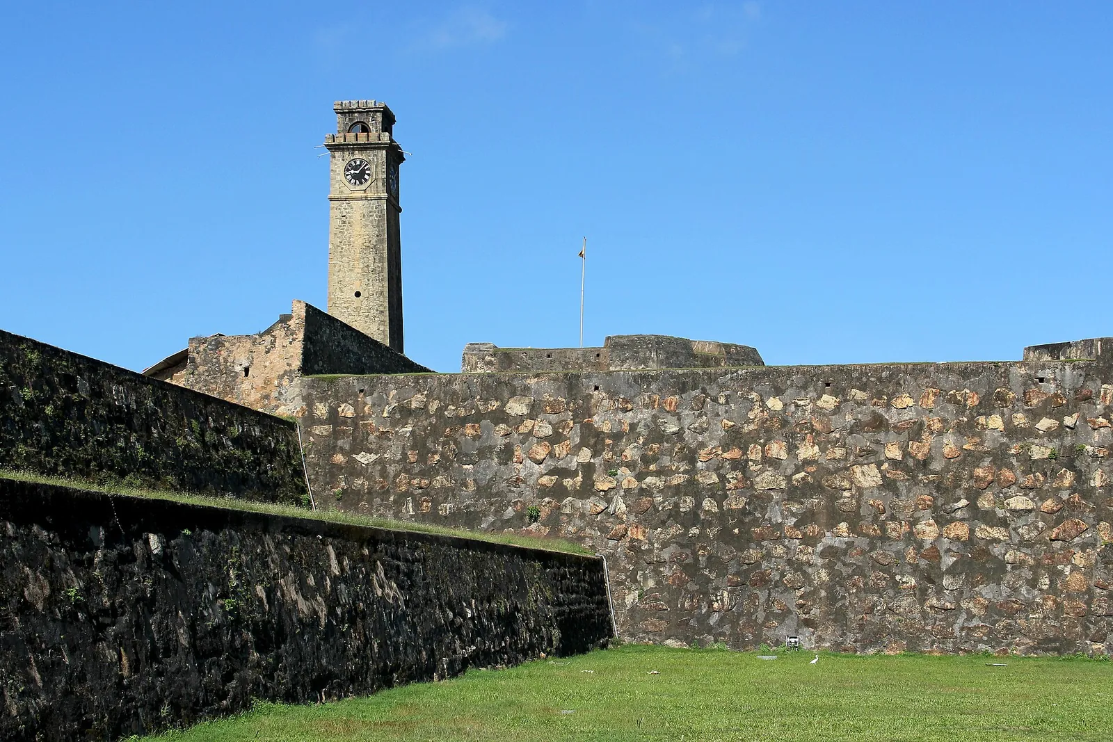 A Galle Fort óratornya egy füves tetejű erődfal fölé emelkedik kék ég alatt