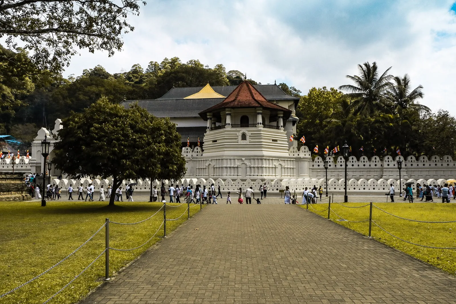 Tandtemplet i Kandy set over en plæne, med den hvide ottekantede pavillon og palmetræer