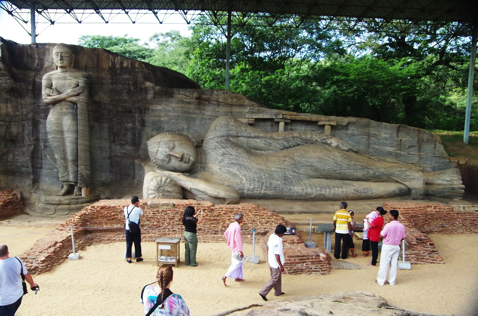 Visitantes ante las figuras de Buda de pie y reclinado talladas en la roca de Gal Vihara, Polonnaruwa