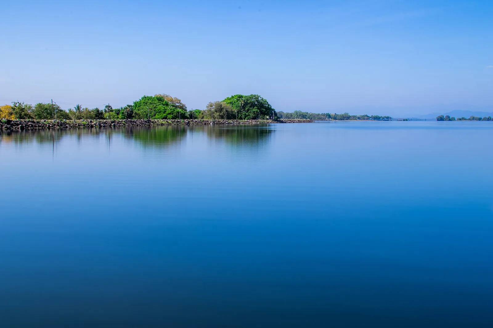 Aguas azules del embalse de Parakrama Samudra con islotes cubiertos de árboles en Polonnaruwa