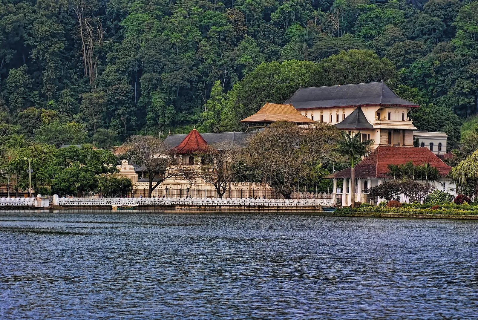 The Temple of the Tooth seen across Kandy Lake with forested hills behind