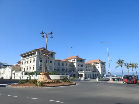 Die weiße Kolonialfassade des Galle Face Hotel an einem von Palmen gesäumten Kreisverkehr in Colombo unter blauem Himmel