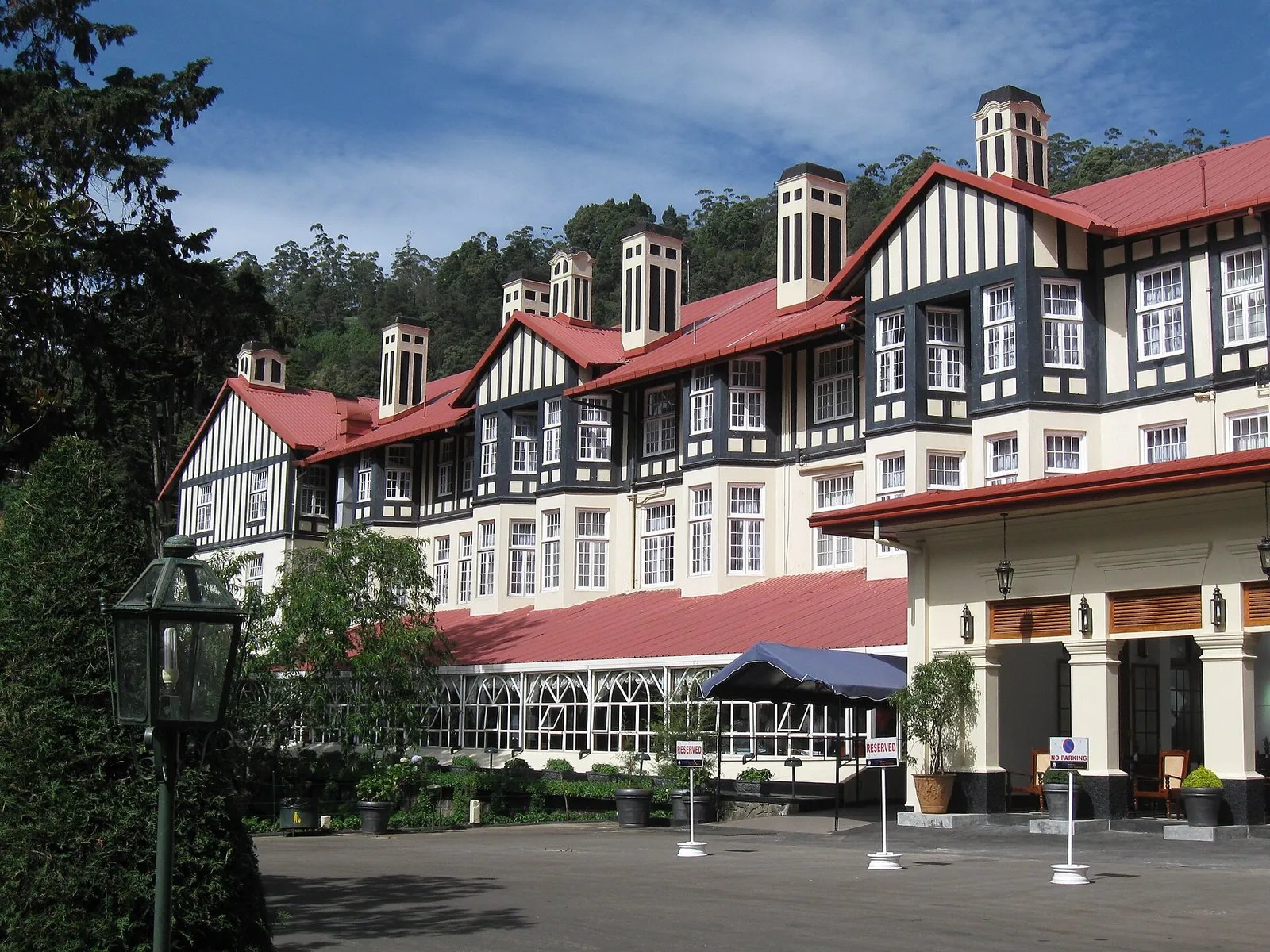 Černobílý hrázděný Grand Hotel v tudorovském stylu v Nuwara Eliya s červenou střechou, při pohledu přes trávník