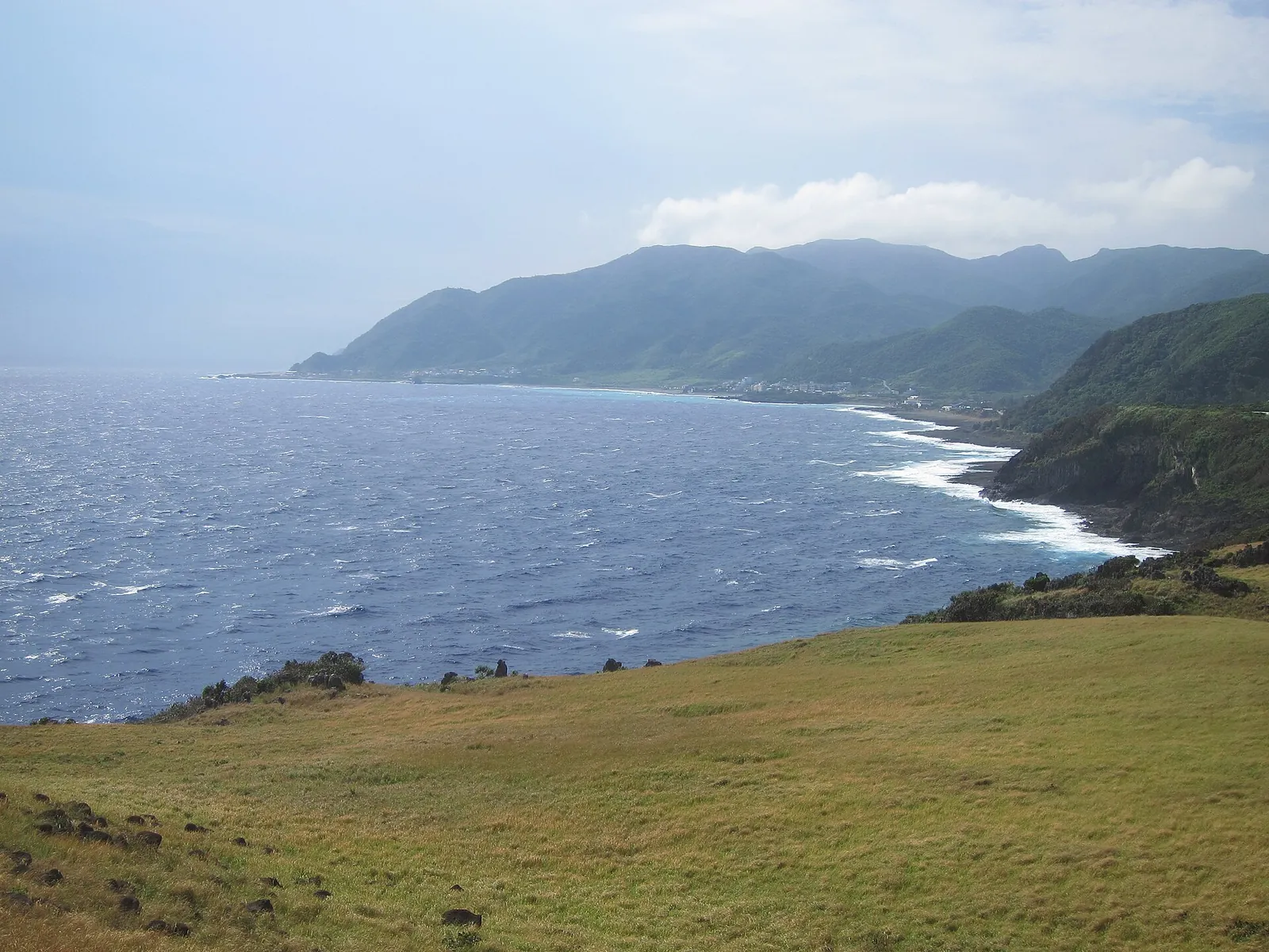 Costa rocosa de Orchid Island bajo una montaña verde