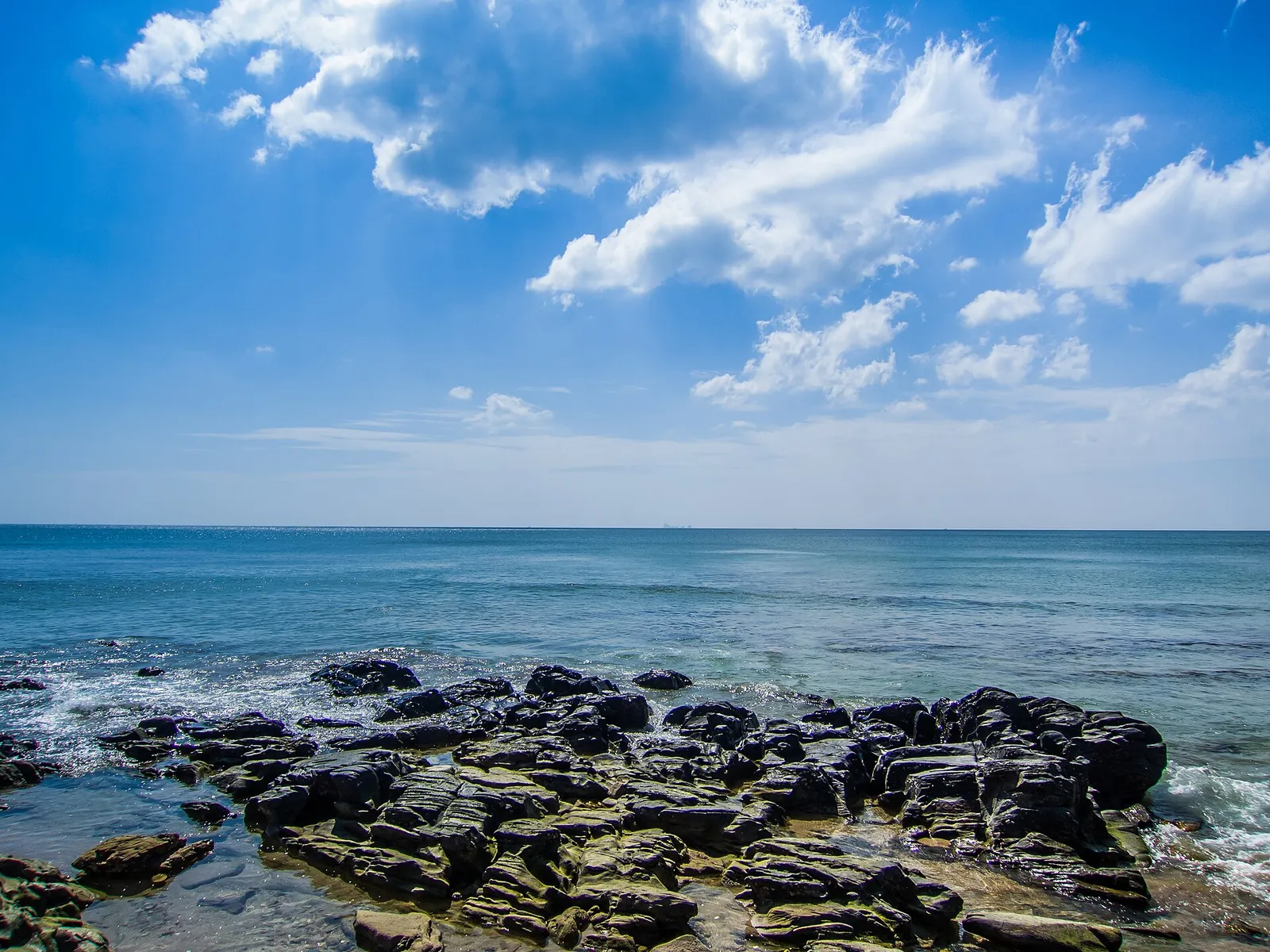 Litorale roccioso e mare blu su Koh Lanta sotto nuvole bianche
