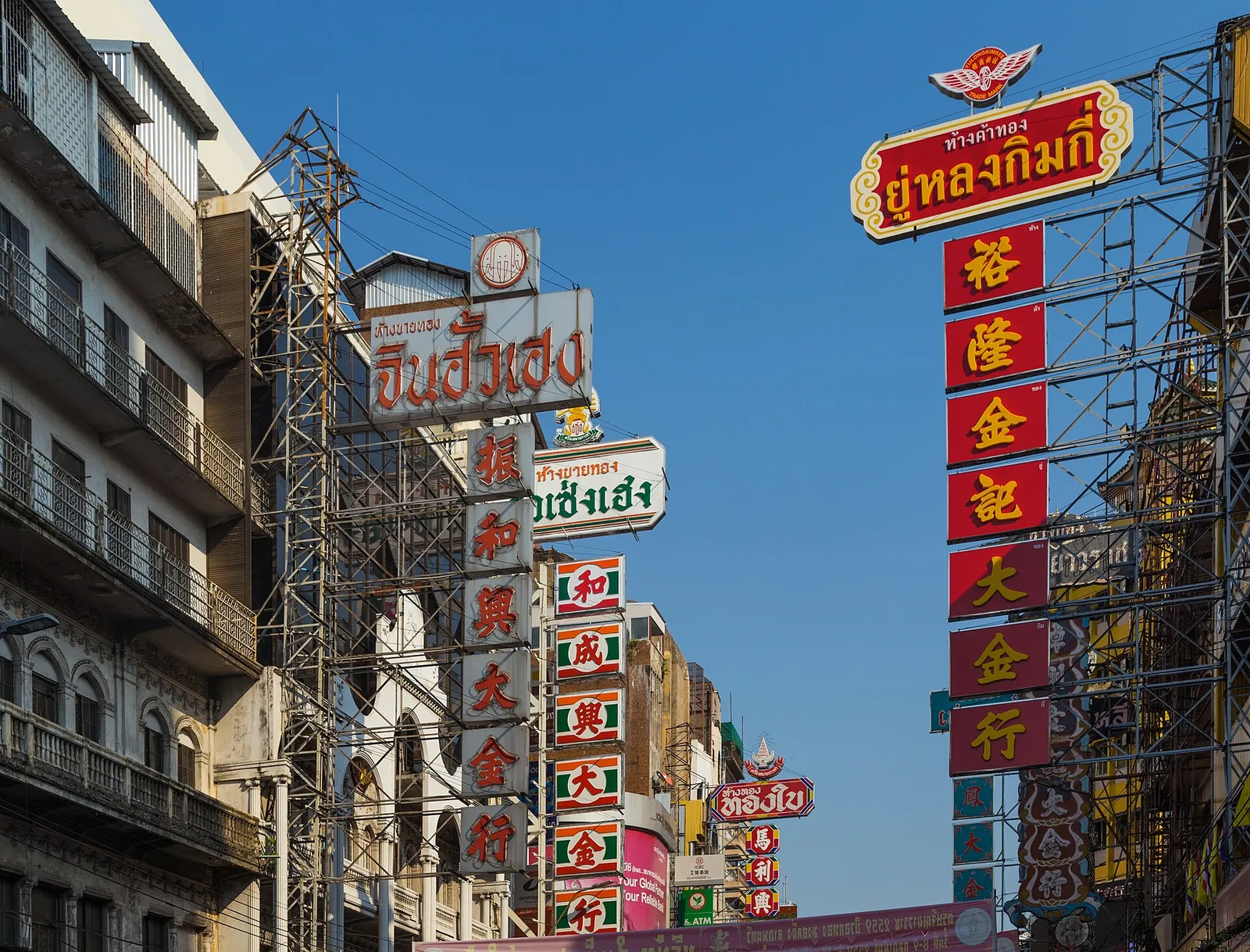 Butikkskilt i gull og rødt stablet over Yaowarat Road i Bangkoks Chinatown