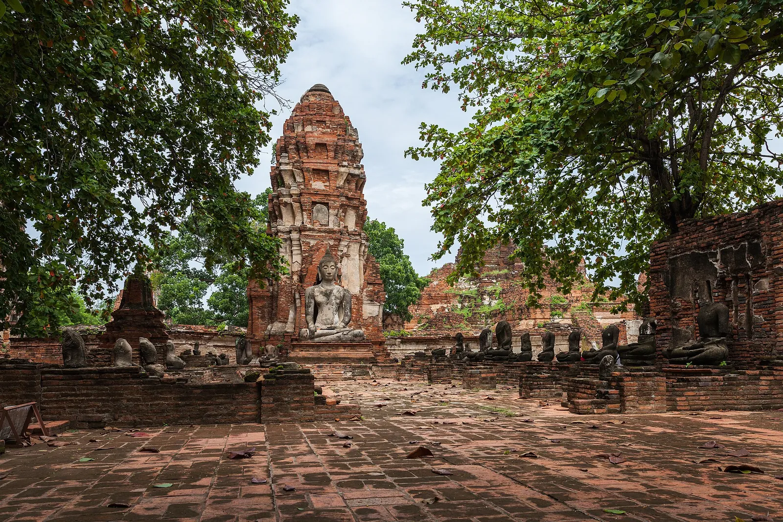 Rovine di mattoni e una torre incorniciata da alberi al Wat Mahathat ad Ayutthaya