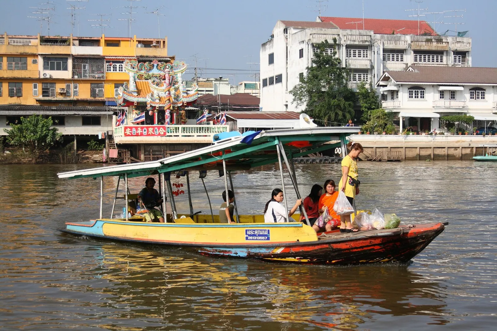 Un traghetto passeggeri su un fiume Ayutthaya accanto agli edifici della città