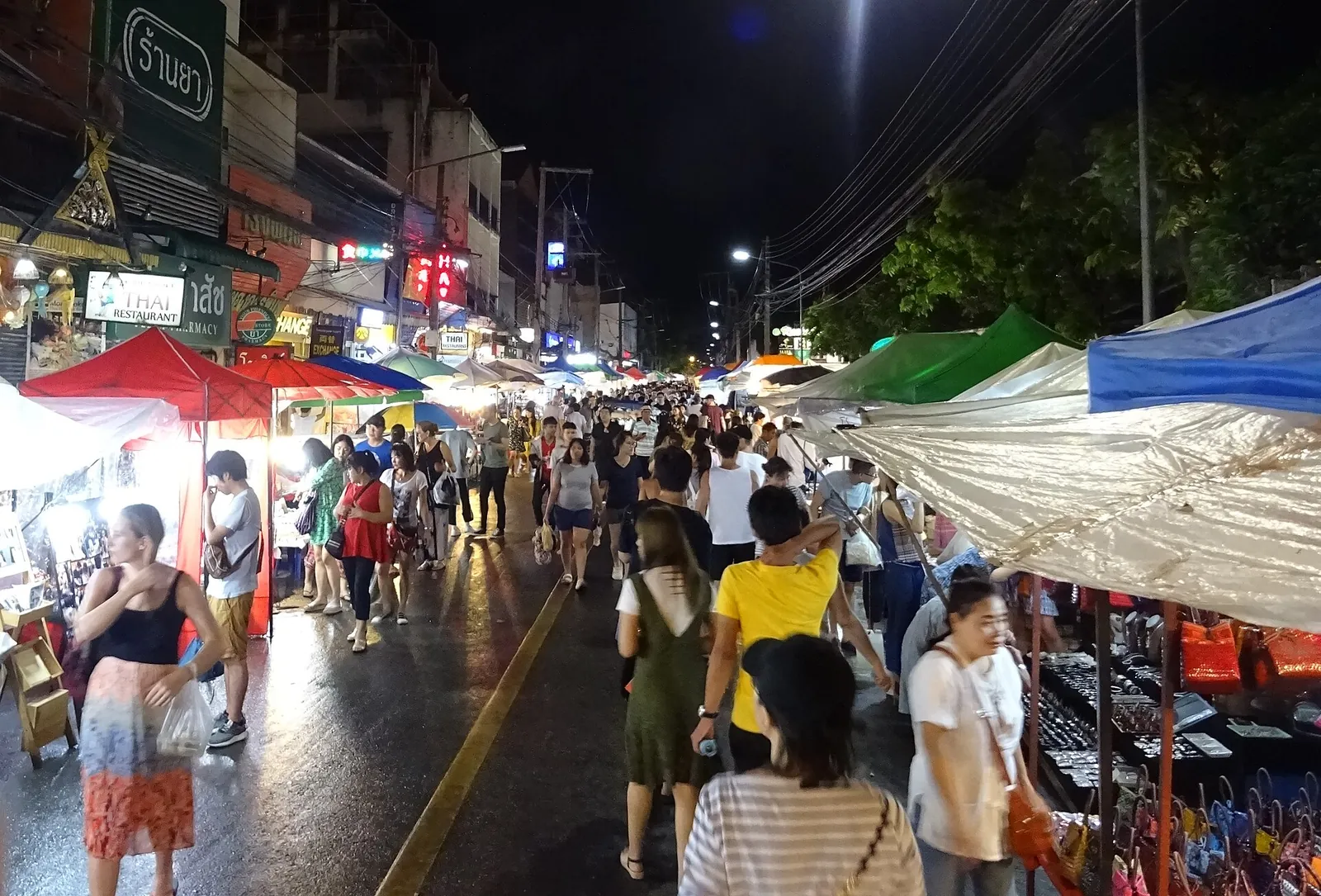 Lidé procházející se mezi stánky nočního trhu v Chiang Mai