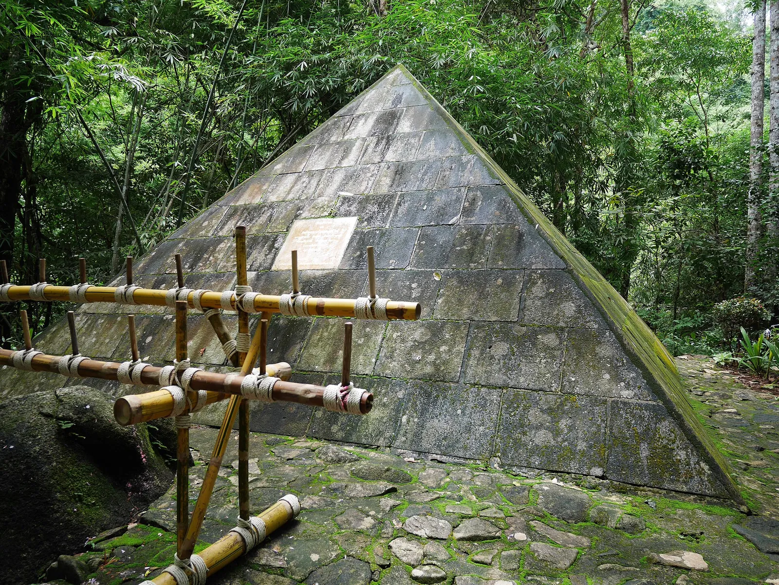 A moss-covered stone pyramid memorial in the forest at Namtok Phlio