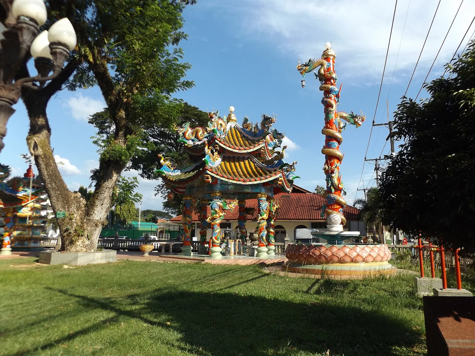 A colourful Chinese shrine with a dragon pillar in a garden in Chanthaburi