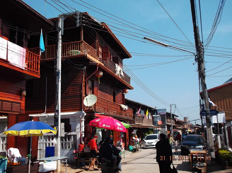 Old two-storey wooden shophouses with balconies along a street in Chiang Khan