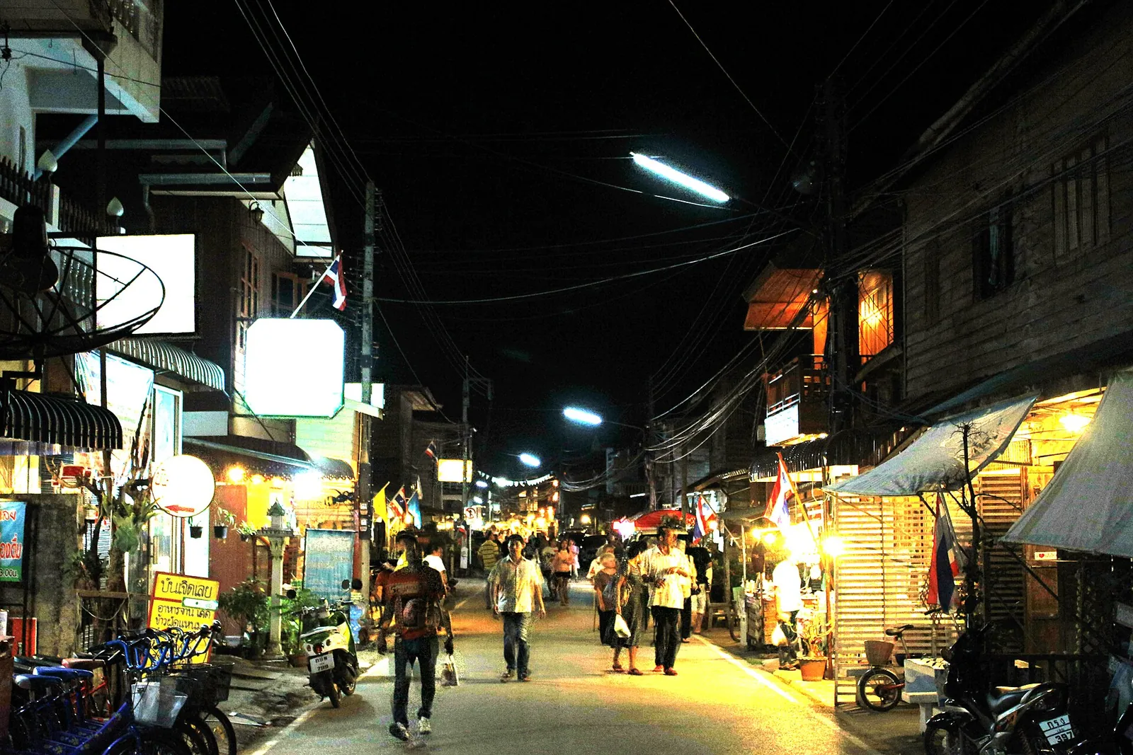Visitors strolling Chiang Khan's walking street at night between lit wooden shops