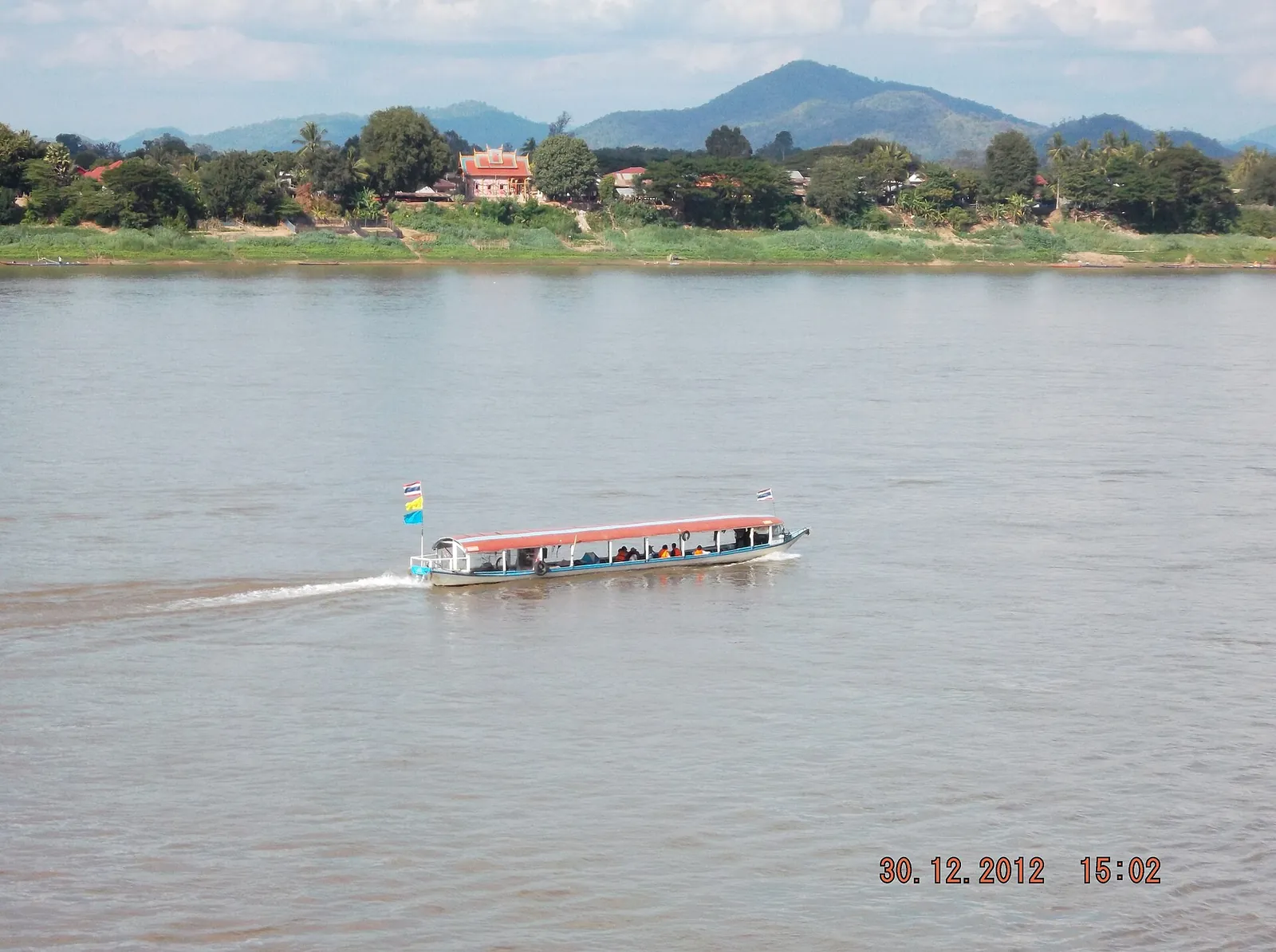 A long passenger boat crossing the wide Mekong at Chiang Khan with hills in Laos beyond
