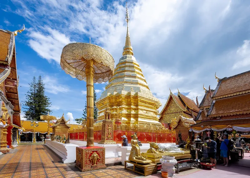 The golden chedi of Wat Phra That Doi Suthep with a gilded parasol under a blue sky