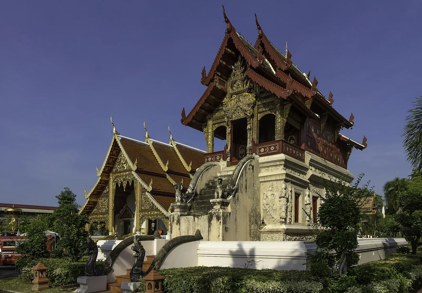 A Lanna-style building with carved wooden gables on a white stucco base at Wat Phra Singh