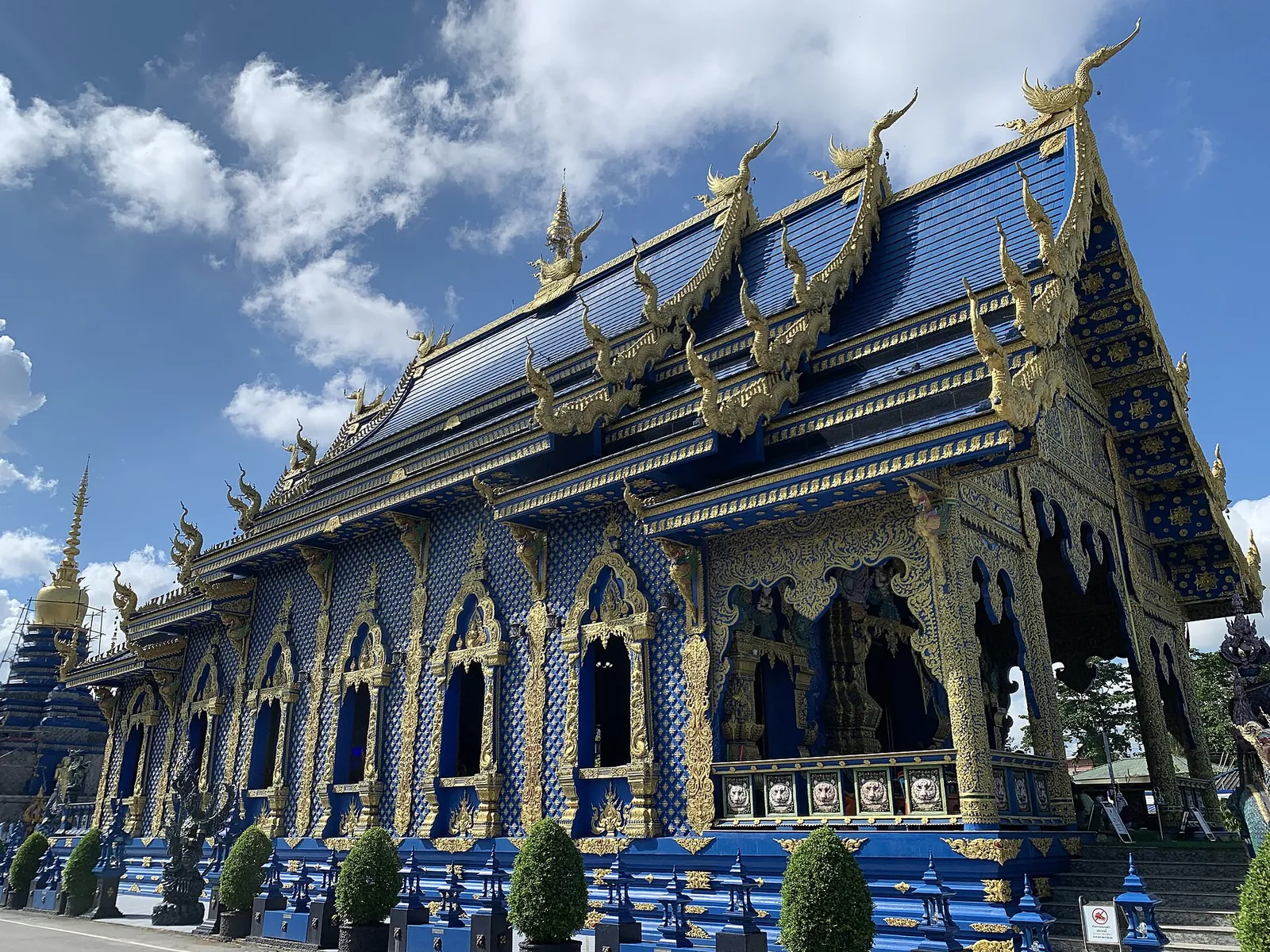 Exterior azul y dorado de Wat Rong Suea Ten bajo un cielo nublado en Chiang Rai