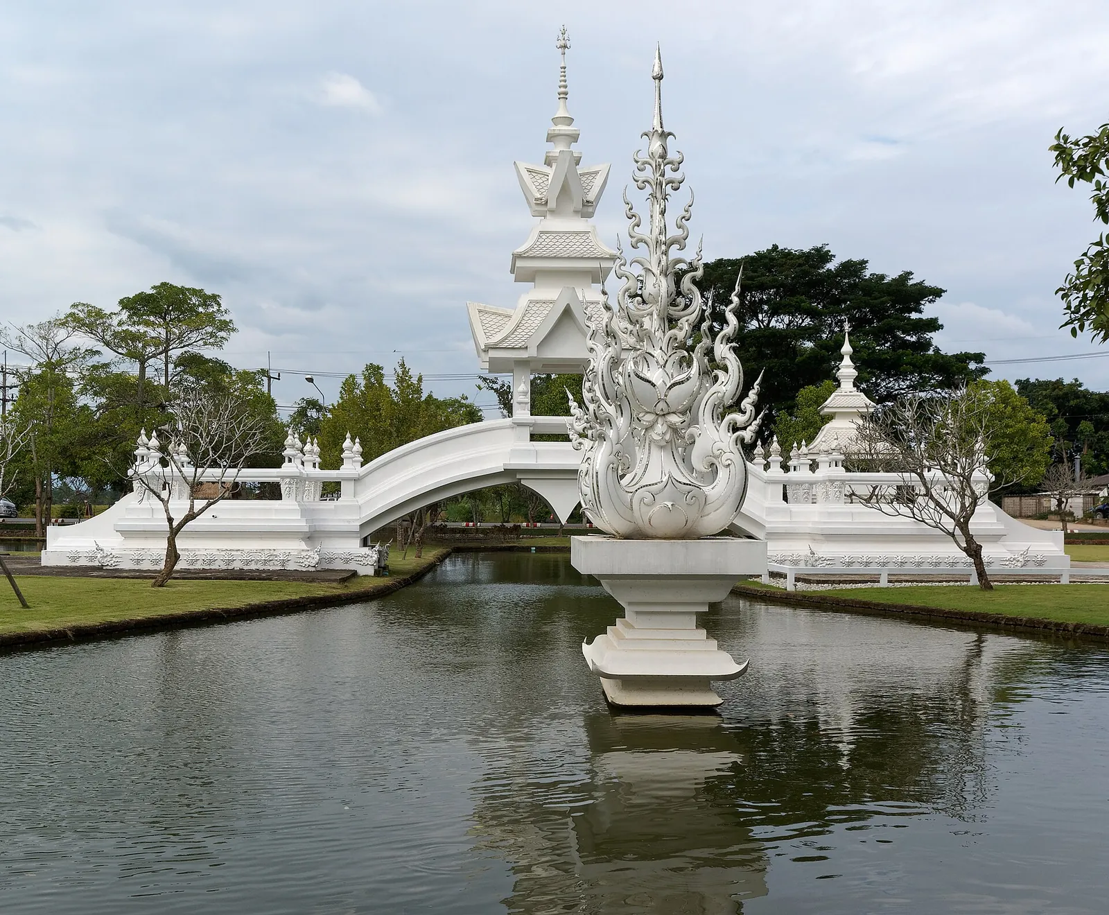 Un puente blanco esculpido sobre el agua en Wat Rong Khun en Chiang Rai