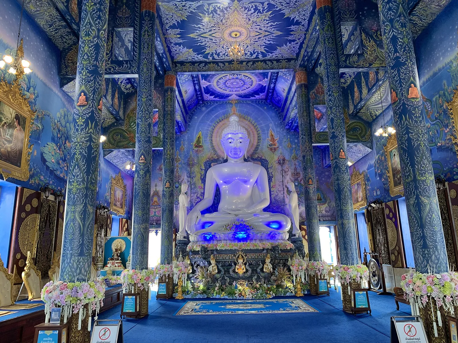 A white seated Buddha inside the blue-painted hall of Wat Rong Suea Ten