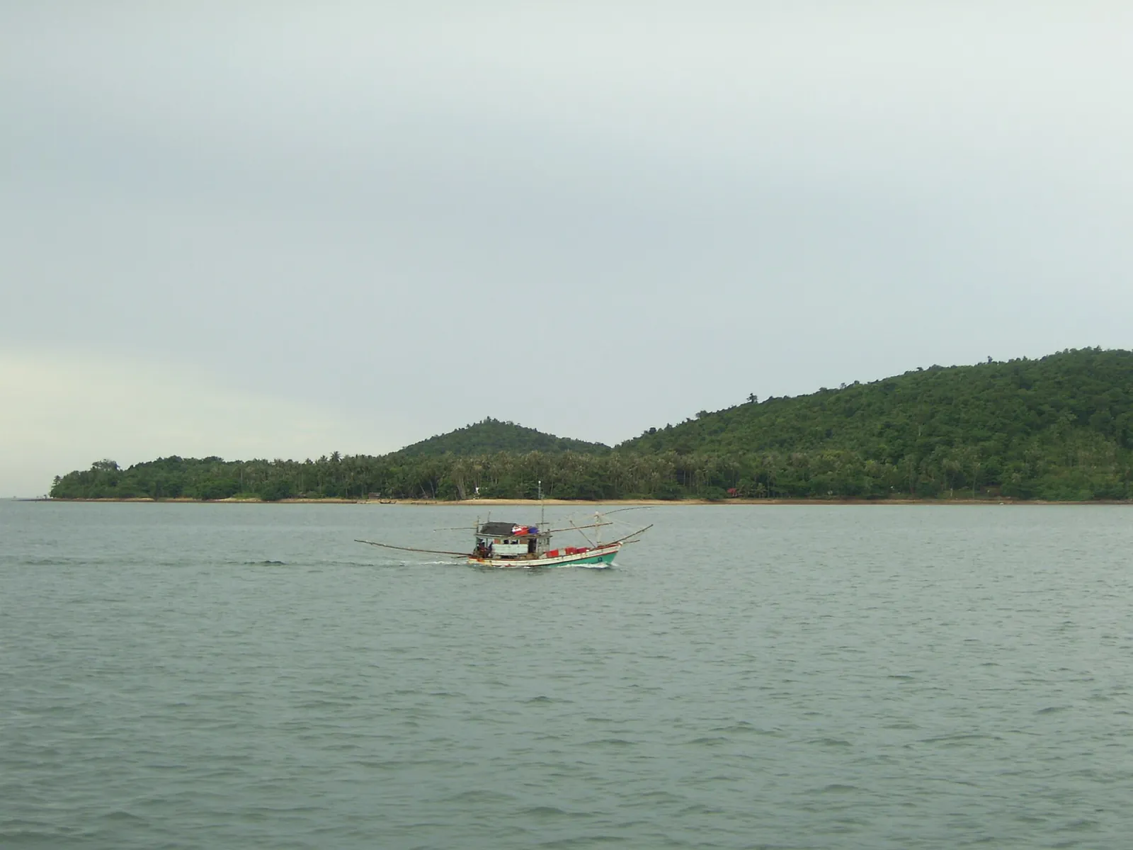 A fishing boat passing forested islands off the Chumphon coast
