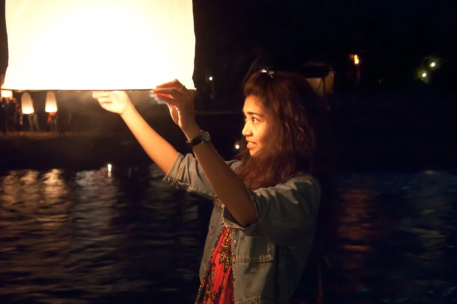 Osoba držící lucernu u vody v Chiang Mai