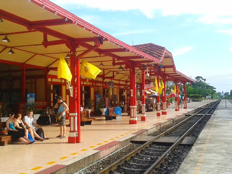 The red and cream wooden platform canopies of Hua Hin railway station under a blue sky