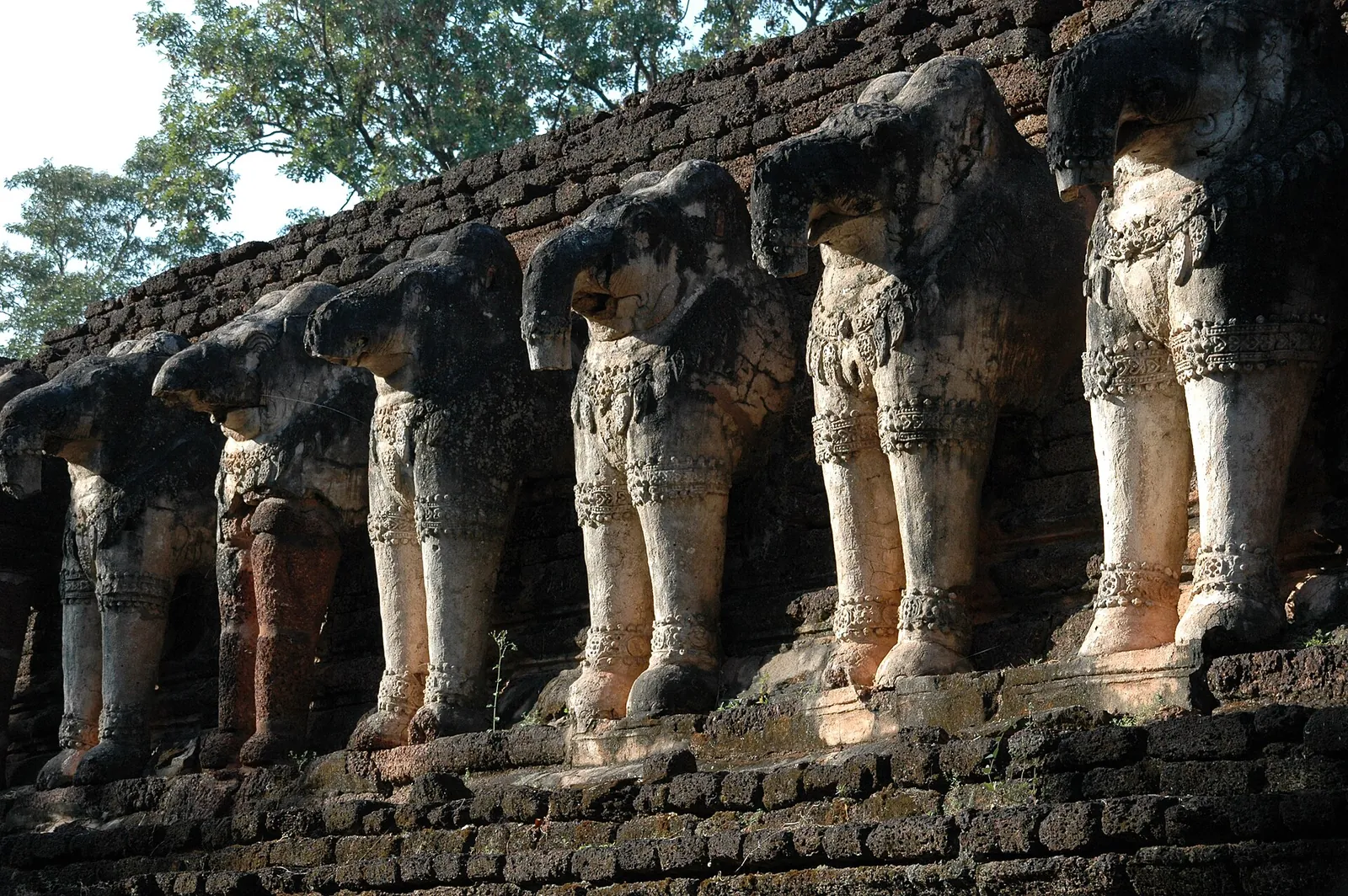 Close view of stucco-covered elephant sculptures projecting from the base of Wat Chang Rob