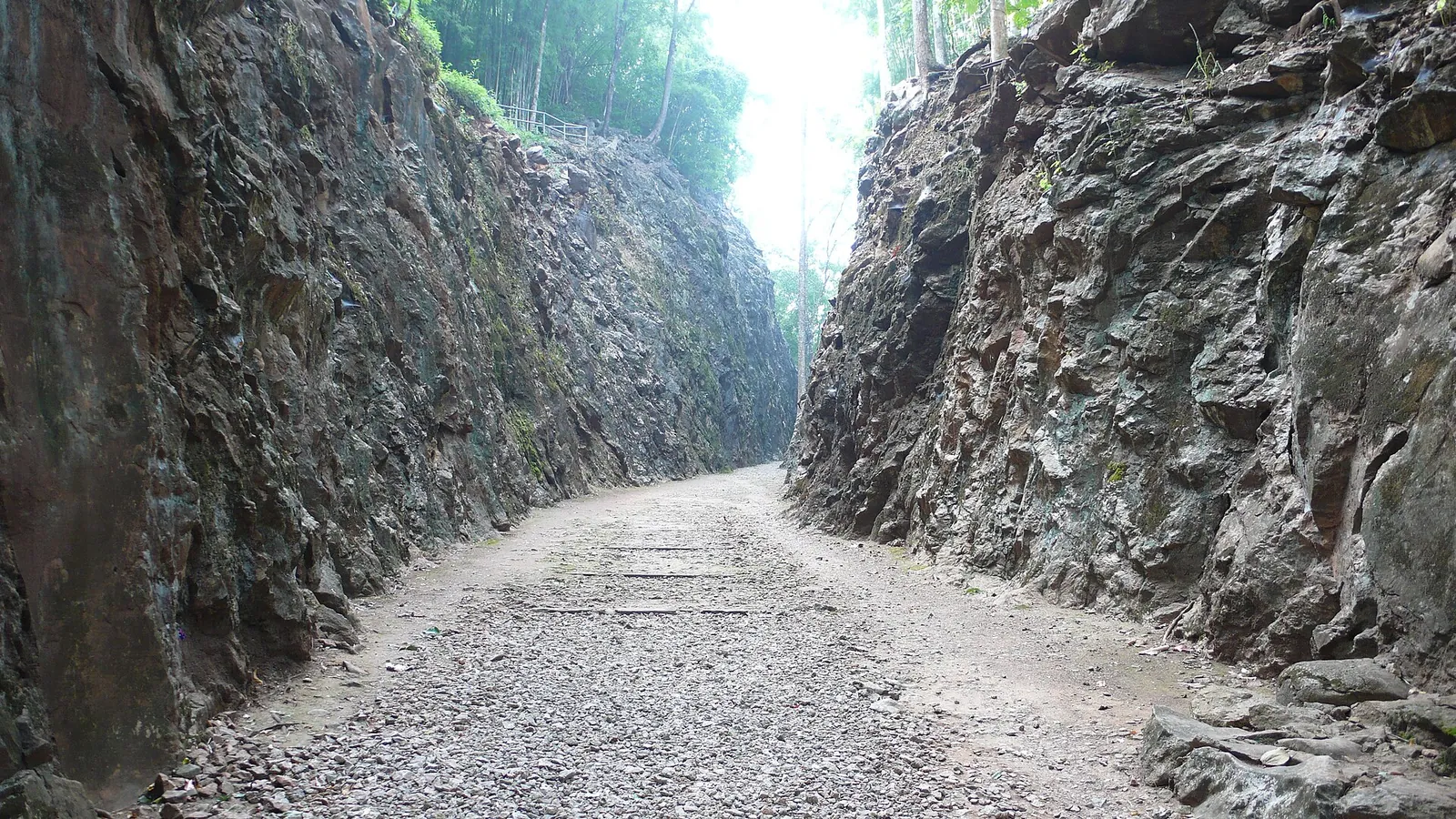 Tranșeea îngustă săpată în stâncă la Hellfire Pass, cu vechiul terasament de cale ferată trecând prin ea