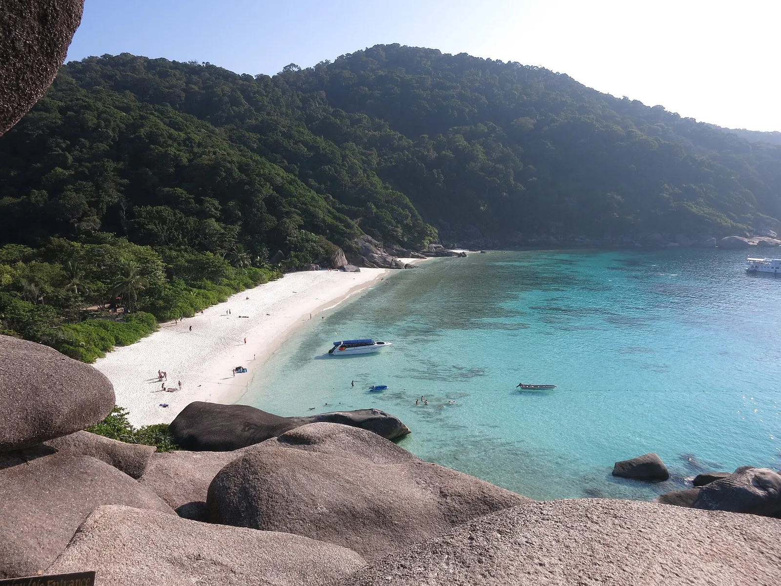 A white-sand beach and clear turquoise water among granite boulders in the Similans