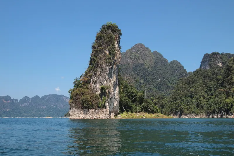 A tall limestone pinnacle rising from the blue water of Cheow Lan Lake
