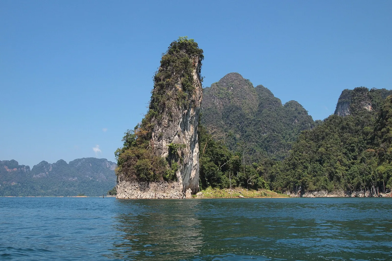 A tall limestone pinnacle rising from the blue water of Cheow Lan Lake