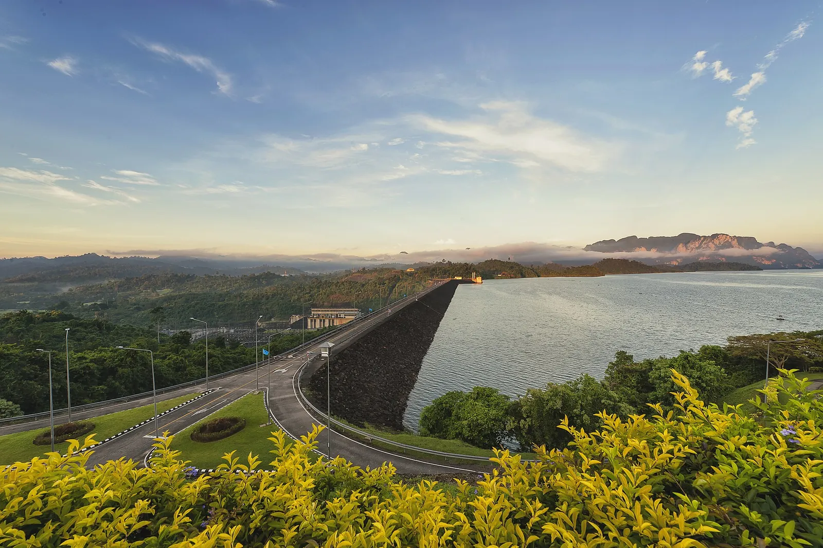 The embankment of Ratchaprapha Dam and its reservoir under an evening sky