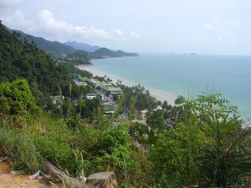 The forested west coast of Koh Chang and a long white beach seen from a hillside