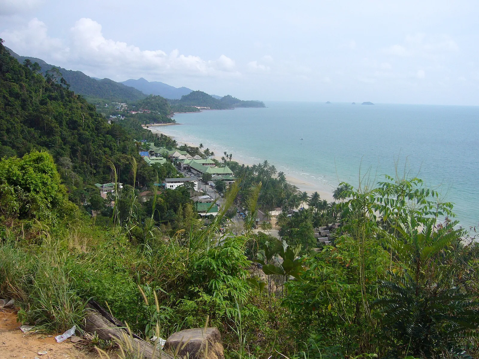 Die bewaldete Westküste von Koh Chang und ein langer weißer Strand von einem Hang aus gesehen