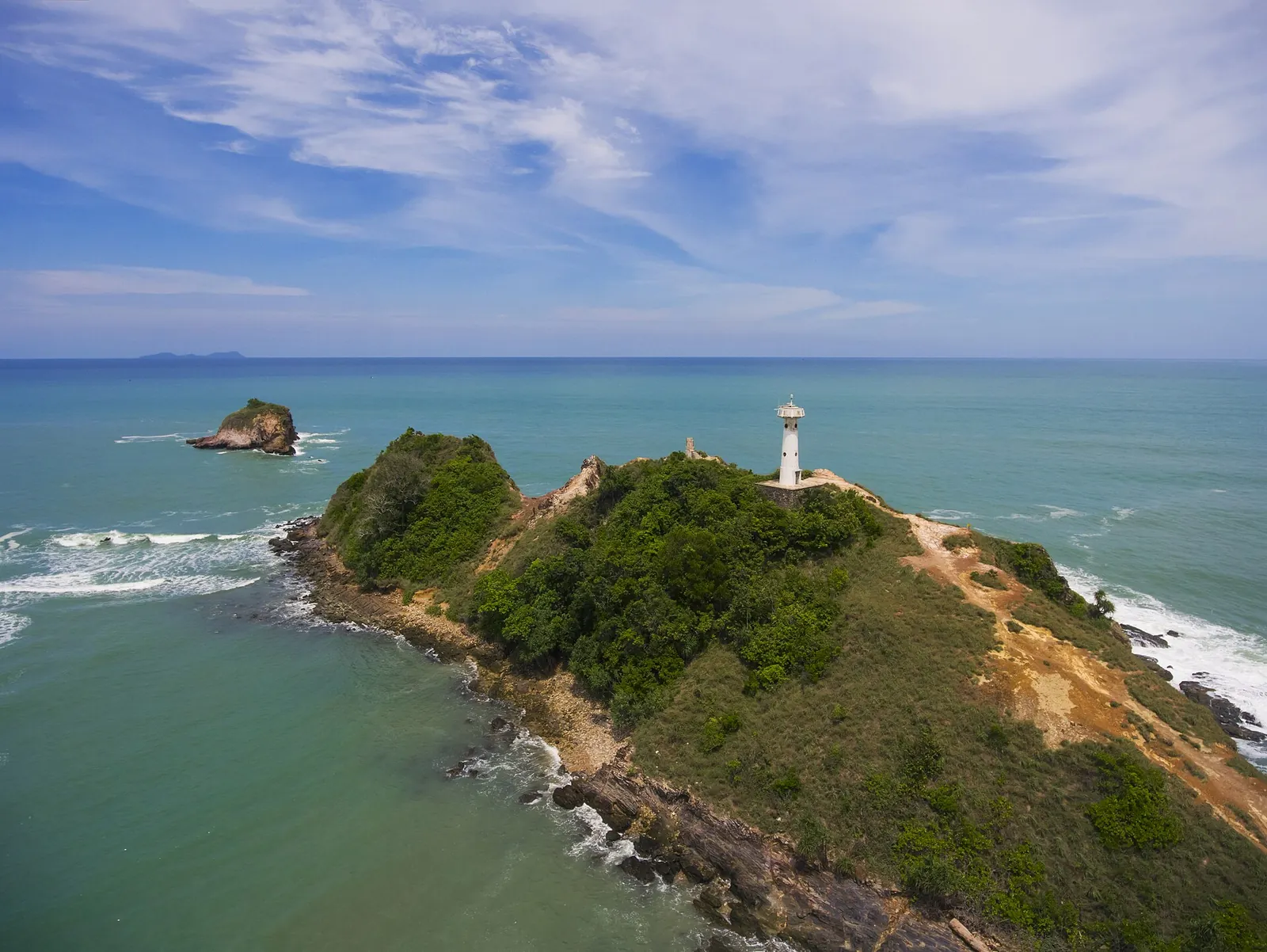 A lighthouse on a green headland above the sea at Mu Ko Lanta National Park