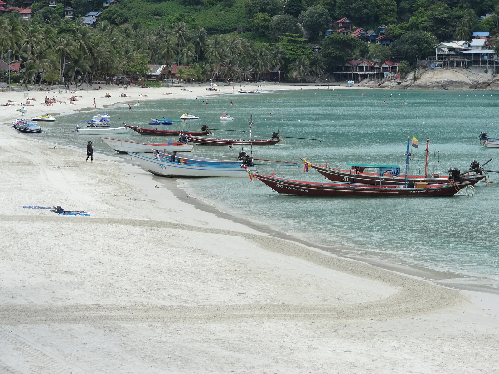 Longtail boats moored along the white sand of Haad Rin Sunrise Beach