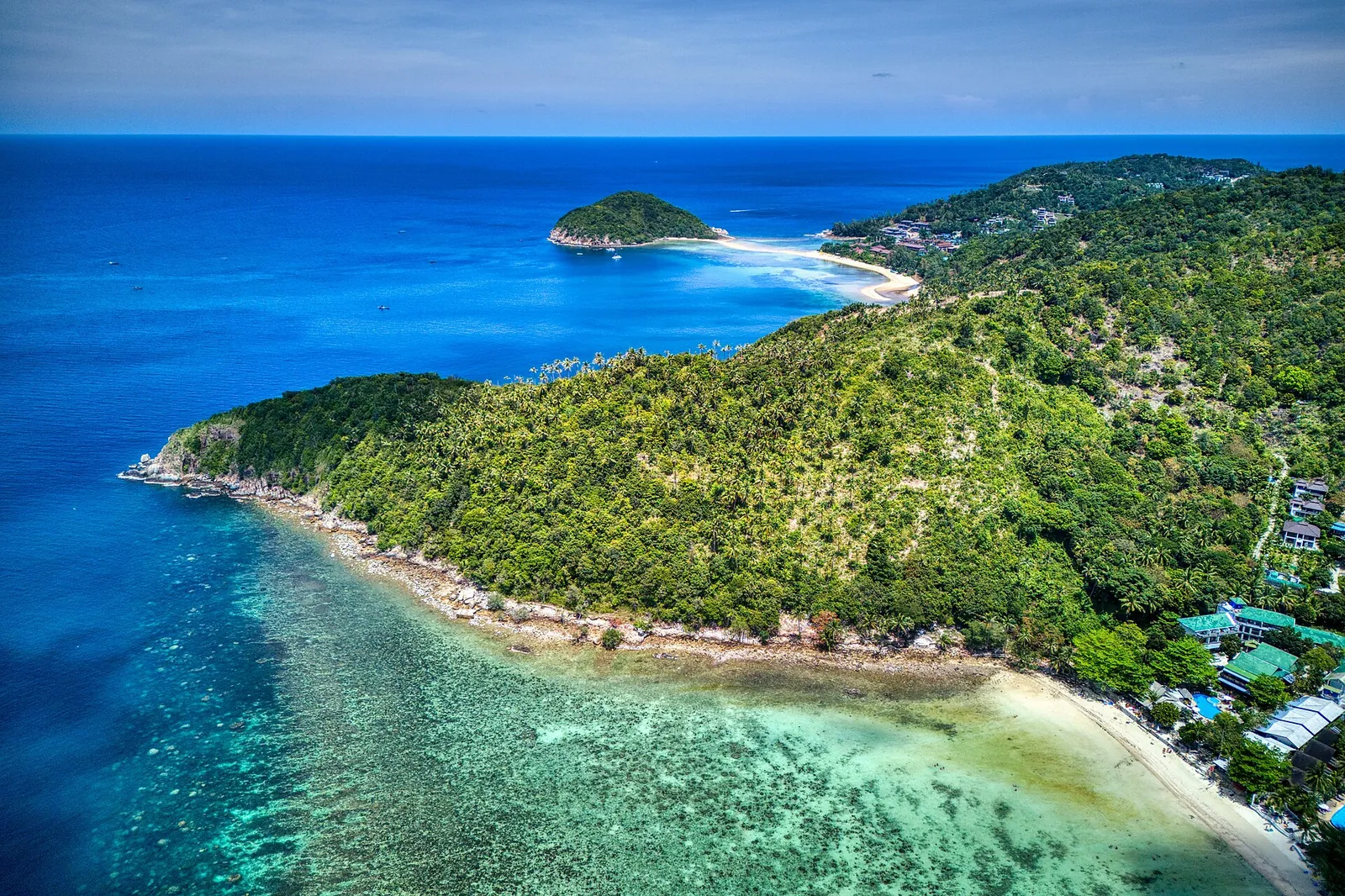 Turquoise reef and a white sand spit along the coast of Koh Phangan from the air