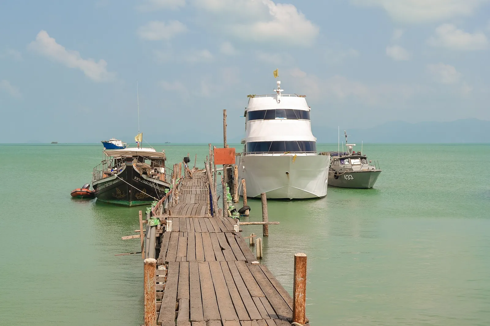 A long wooden pier with boats moored at Bophut on the north coast of Koh Samui