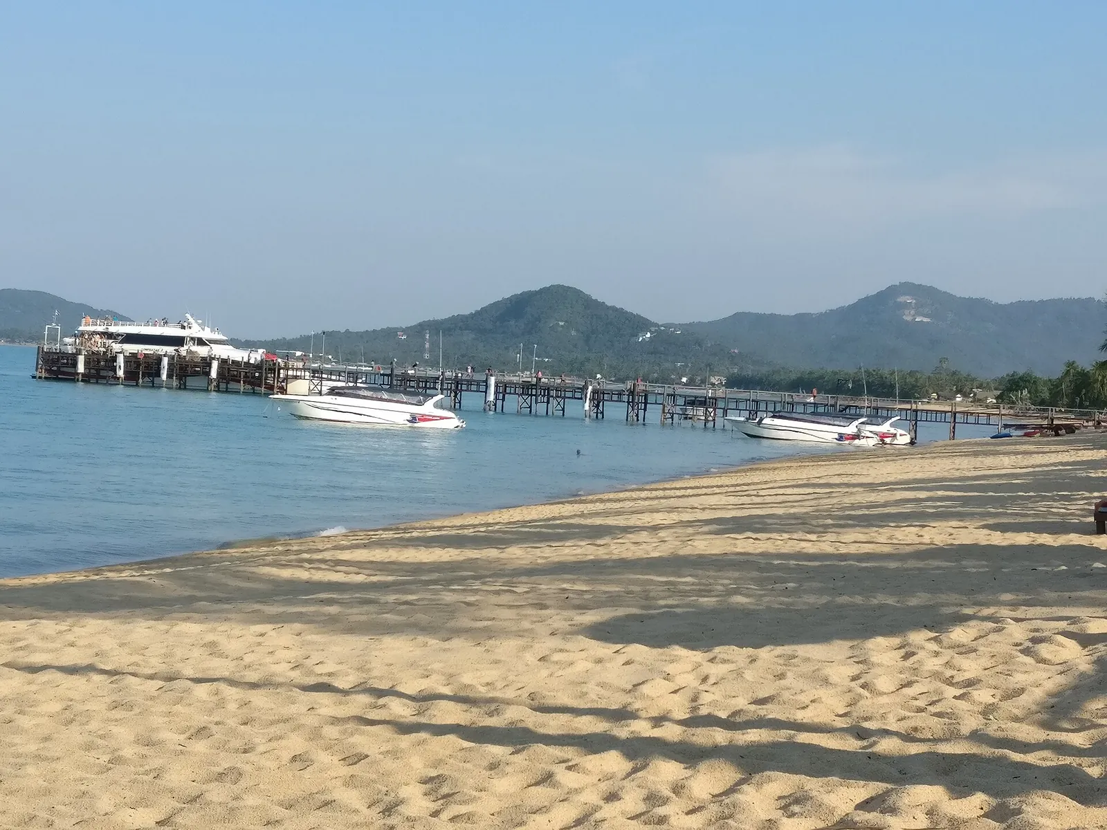 The sandy beach of Mae Nam with a pier and hills on the north coast